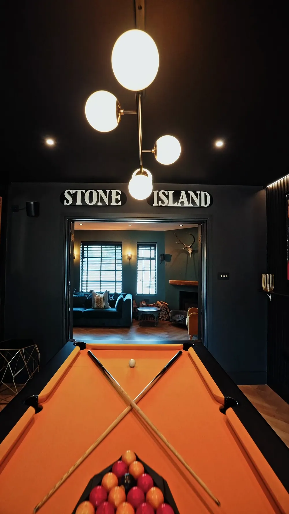 A dark games room with a pool table and a built in fish tank